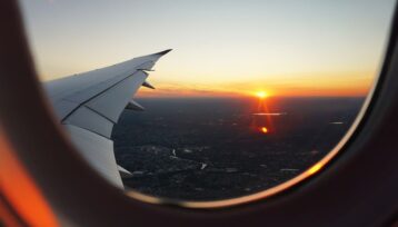 Flygplansvinge och solnedgång sedda genom ett flygplansfönster