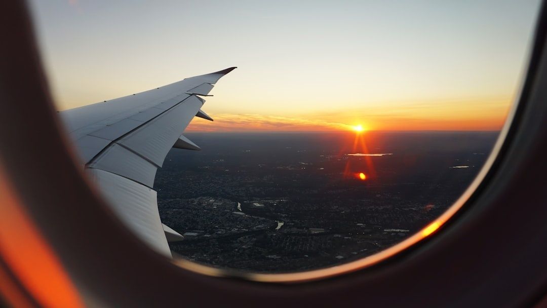 Flygplansvinge och solnedgång sedda genom ett flygplansfönster