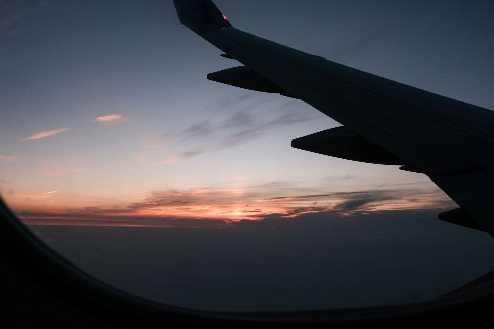 Flygplansvinge i siluett mot en färgstark solnedgång