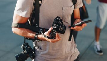 Resefotograf håller en kamera och granskar en mobiltelefon