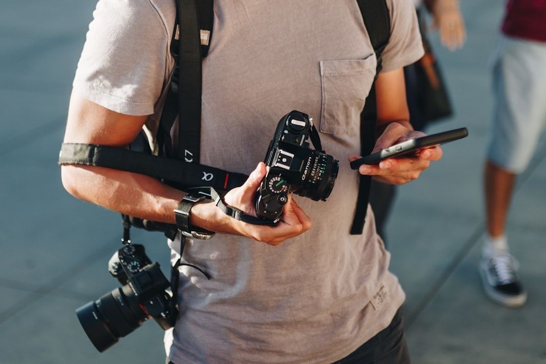 Resefotograf håller en kamera och granskar en mobiltelefon