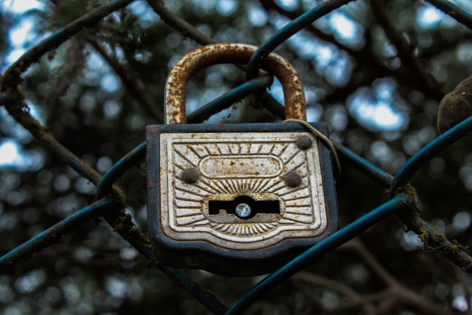 Rostigt hänglås på ett stängsel, symboliserar säkerhet för värdesaker.